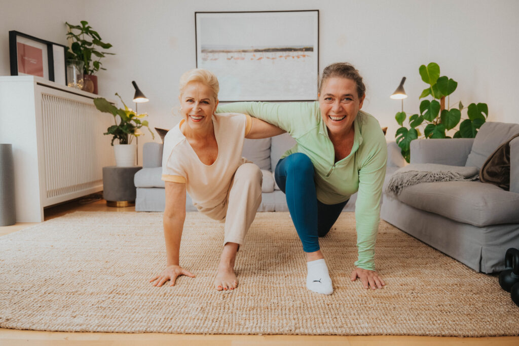 Sportliche Freundinnen trainieren zu Hause 