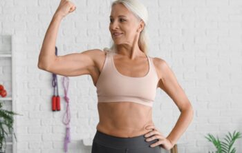 Sportliche, reife Frau macht kraftvolle Geste mit ihrem Arm
