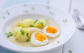 Eier mit Petersilienkartoffeln auf dem Teller mit Senfsoße angerichtet