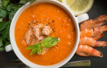 Tomatencremesuppe mit Garnelen und Basilikum angerichtet im Suppenteller