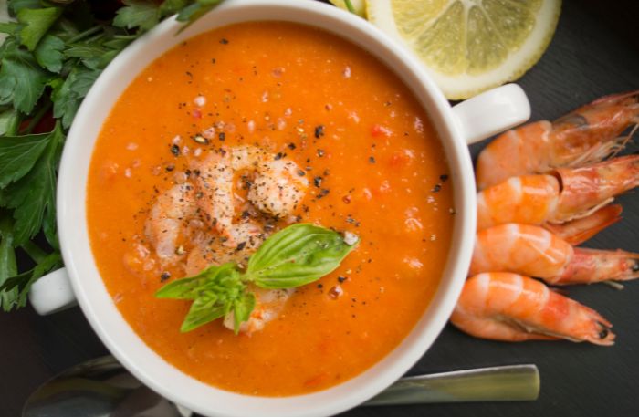Tomatencremesuppe mit Garnelen und Basilikum angerichtet im Suppenteller