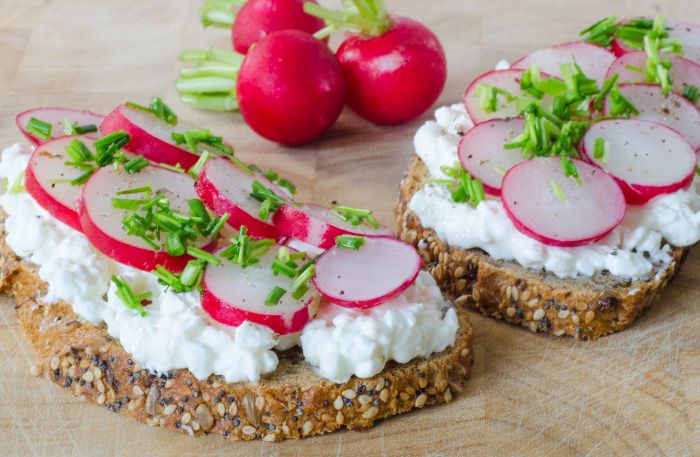 Scheiben Vollkornbrot mit Hüttenkäse bestrichen und Radieschengarnitur
