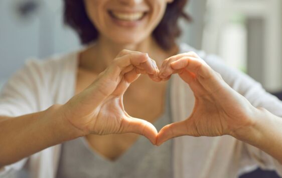 Eine Frau formt mit beiden Händen ein Herz um die Herzgesundheit von Frauen zu symbolisieren