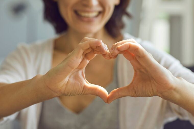 Eine Frau formt mit beiden Händen ein Herz um die Herzgesundheit von Frauen zu symbolisieren