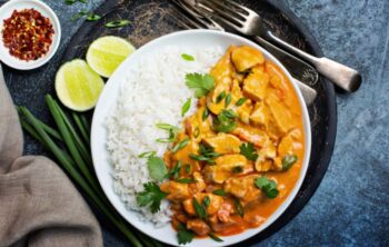Curry mit Hähnchen und Ananas auf einem Teller angerichtet mit Reis