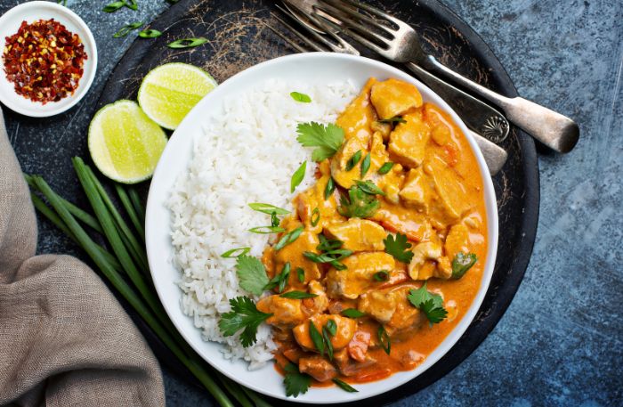 Curry mit Hähnchen und Ananas auf einem Teller angerichtet mit Reis